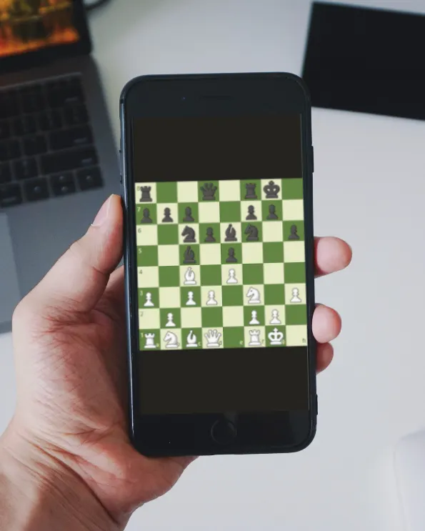 Hand holding a phone with a chess board on screen