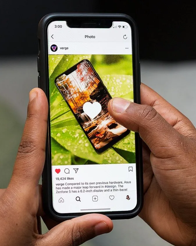 Hands holding a phone showing a photo feed